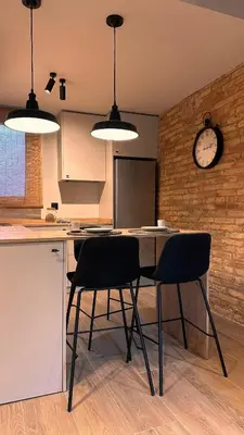 a kitchen with two chairs and a table with a clock on the wall at La Fira - Paralelo 2 in Barcelona