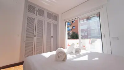 a white bedroom with a bed and a large window at SeaHomes Vacations - Villa Chill & Pool 200m Beach in Pineda de Mar