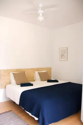 a bedroom with a large bed with a blue blanket at Apartamentos Villa Valle in Castelldefels