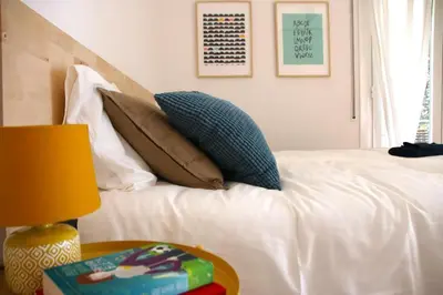 a bedroom with a bed with pillows and a table at Apartamentos Villa Valle in Castelldefels
