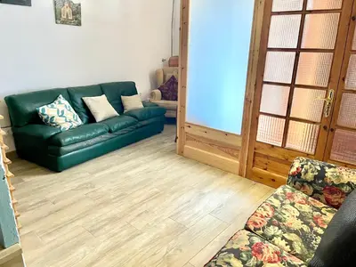 a living room with a green couch and wooden floors at Old Town Montserrat in Collbató