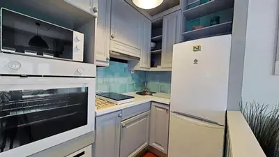 a kitchen with white cabinets and a white refrigerator at For Sea Lovers in Cubelles