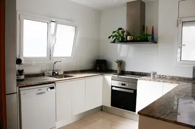 a kitchen with white cabinets and a black appliance at Cozy Apartment Rocamar in Sant Pere de Ribes