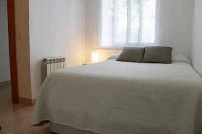 a bedroom with a white bed with a window at Cozy Apartment Rocamar in Sant Pere de Ribes