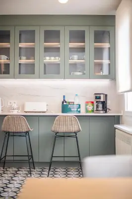 a kitchen with green cabinets and two stools at Ático dúplex con cinco dormitorios in Barcelona
