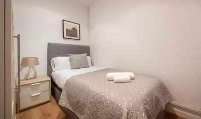 a small bedroom with a bed and a night stand at Apartamento de cuatro dormitorios en Calle Aribau You Stylish Apartments in Barcelona