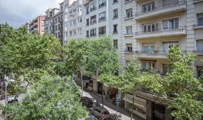 an apartment building with trees in front of it at Apartamento de cuatro dormitorios en Calle Aribau You Stylish Apartments in Barcelona