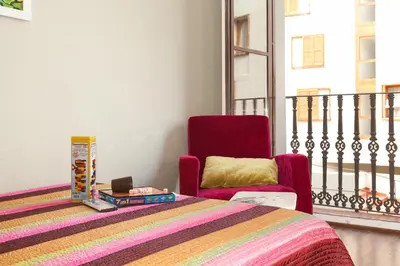 a bedroom with a bed and a chair and a window at El Born Apartment - Santa Caterina Market - Walk to Cathedral & Picasso Museum in Barcelona