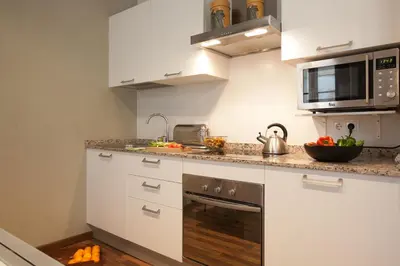 a kitchen with white cabinets and a microwave at El Born Apartment - Santa Caterina Market - Walk to Cathedral & Picasso Museum in Barcelona