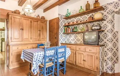 a kitchen with a table with blue chairs and a tv at Nice Home In Arenys De Munt in Arenys de Munt