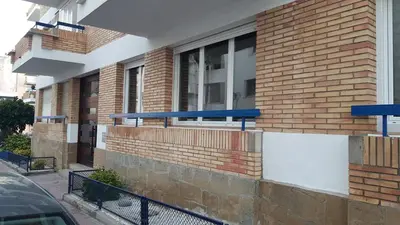 a brick building with blue benches on the side of it at Sitges Oasi in Sitges