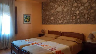 a bedroom with two beds and a painting on the wall at Can Bicicleta de Dalt in Olesa de Bonesvalls