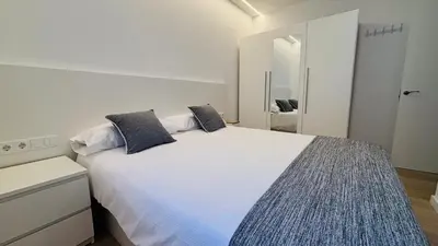 a white bedroom with a large white bed with two pillows at Apartamento familiar by prestigi in Terrassa
