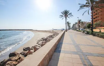 a sidewalk next to a beach with palm trees at Cozy Home In Calafell With Wifi in Calafell