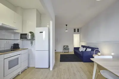 a kitchen and living room with a white refrigerator and a blue couch at BBarcelona Mallorca Flats in Barcelona