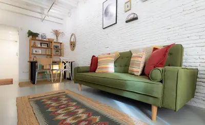 a living room with a green couch with colorful pillows at Stay U-nique Apartments Llibertat in Barcelona