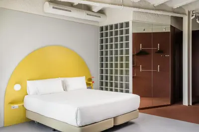 a bedroom with a white bed and a yellow wall at BYPILLOW Flamant in Barcelona