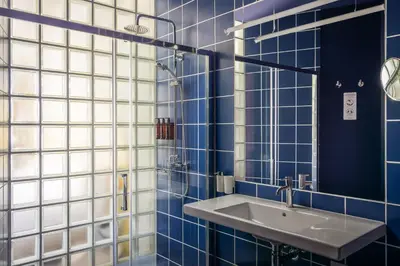 a blue tiled bathroom with a sink and a mirror at BYPILLOW Flamant in Barcelona