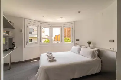 a white bedroom with a large bed and windows at Stay U-nique Apartment Creu Coberta in Barcelona