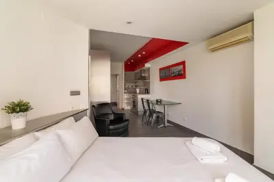 a bedroom with a white bed and a table at Stay U-nique Apartment Creu Coberta in Barcelona