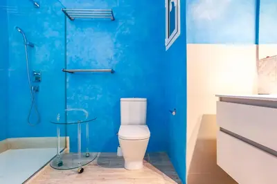a blue bathroom with a toilet and a shower at Love in Cuba in Sitges