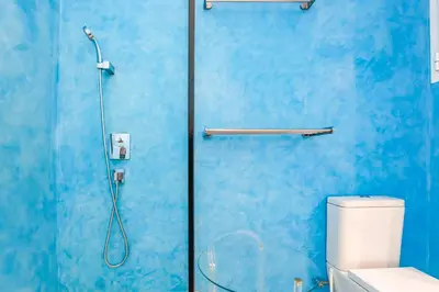 a blue bathroom with a shower with a glass door at Love in Cuba in Sitges