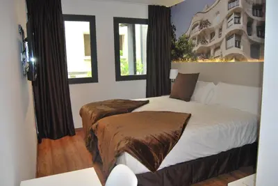 a bedroom with a bed and two windows at Hotel BESTPRICE Gracia in Barcelona