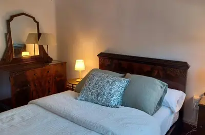 a bedroom with a bed with a wooden headboard and a mirror at Can Puig Barata, Aiguafreda in Aiguafreda