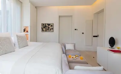 a white bedroom with a large bed and a couch at ABaC H&R Barcelona Monument in Barcelona
