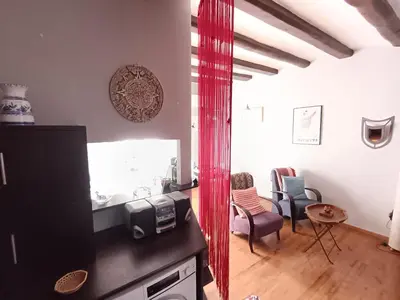 a kitchen and living room with a red curtain at Ca la Fiona in Monistrol