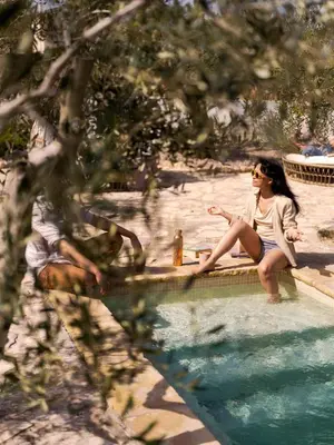 a woman sitting next to a swimming pool at Soul Farm Mas els Igols in Torrellas de Foix