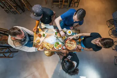 a group of people standing around a table eating pizza at Safestay Barcelona Passeig de Gràcia in Barcelona
