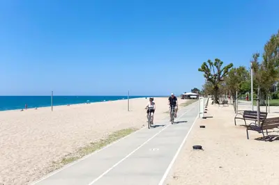 two people riding bikes down a sidewalk on the beach at Perfect Apartment near the beach and Barcelona in Pineda de Mar