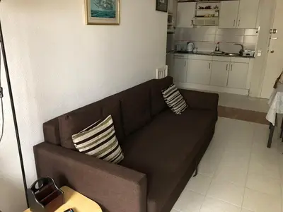 a brown couch in a living room with a kitchen at Perfect Apartment near the beach and Barcelona in Pineda de Mar