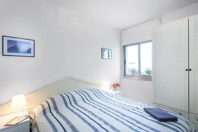 a white bedroom with a bed and a window at Perfect Apartment near the beach and Barcelona in Pineda de Mar