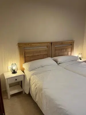 a bedroom with two beds and a night stand with two lamps at Can Sura in Campíns