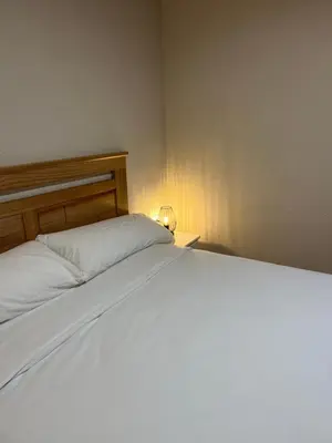 a bedroom with a white bed with a wooden headboard at Can Sura in Campíns