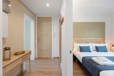 a bedroom with two beds with blue pillows and a table at Flateli Pelayo H7 in Barcelona