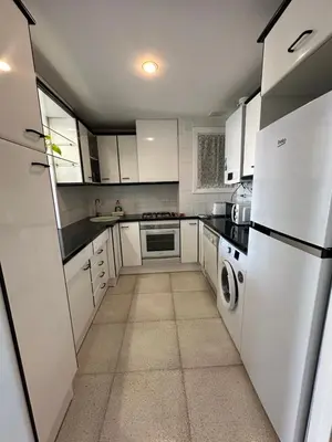 a small kitchen with white cabinets and appliances at Can Xifre 1 in Arenys de Mar
