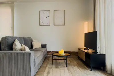 a living room with a gray couch and a table at Novus Homes Barcelona Plaza España in Barcelona