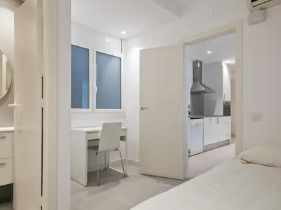 a white bedroom with a desk and a bed at Winahost Barcelona Pedralbes in Barcelona