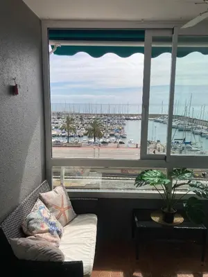a couch in front of a large window with a harbor at Masnou nice view big apartment in Masnou