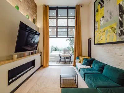 a living room with a green couch and a tv at Luxury 2 Story Apartment Near Passeig de Gracia in Barcelona