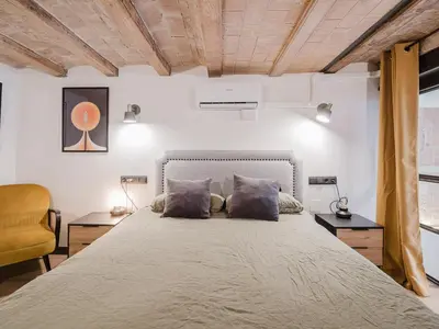 a bedroom with a large bed and a yellow chair at Luxury 2 Story Apartment Near Passeig de Gracia in Barcelona