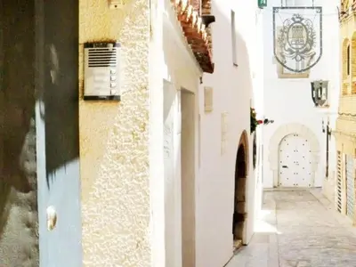 an alley with a white building and a door at Pis Sitges centre in Sitges