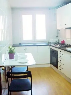 a white kitchen with a table and two chairs at Pis Sitges centre in Sitges
