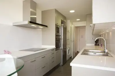 a white kitchen with a sink and a counter top at Modern apartment in Diagonal Mar in Barcelona