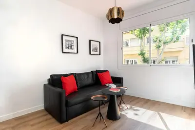 a living room with a black couch and a window at Dúplex Deluxe Apartment in Badalona
