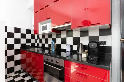 a kitchen with red cabinets and a checkered wall at Dúplex Deluxe Apartment in Badalona