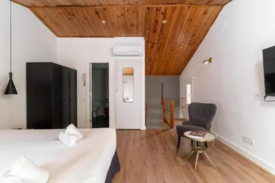 a bedroom with a bed and a chair at Dúplex Deluxe Apartment in Badalona